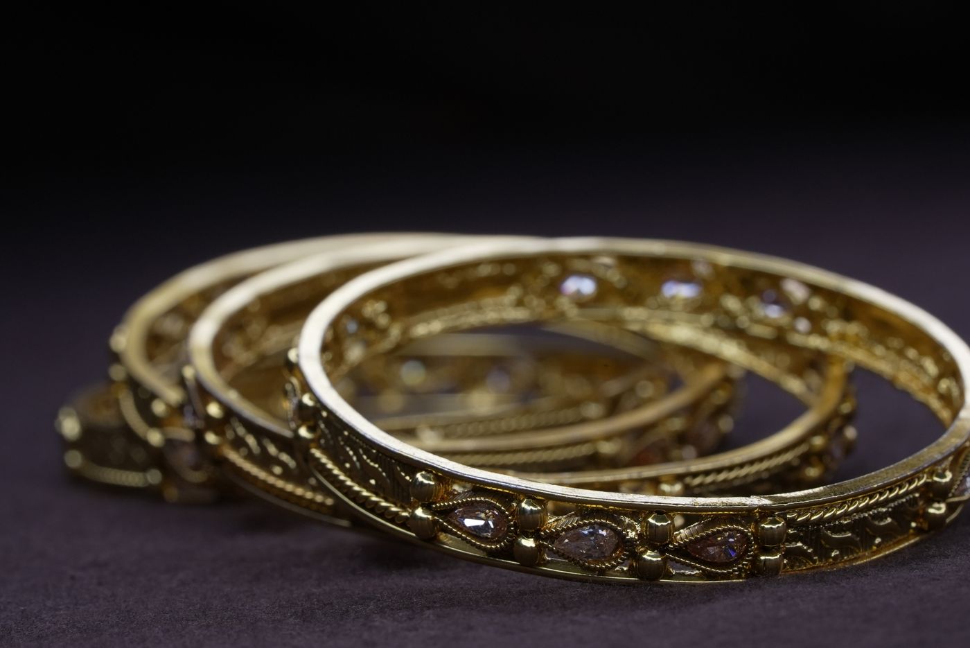 Ornate gold bangles on a dark ground